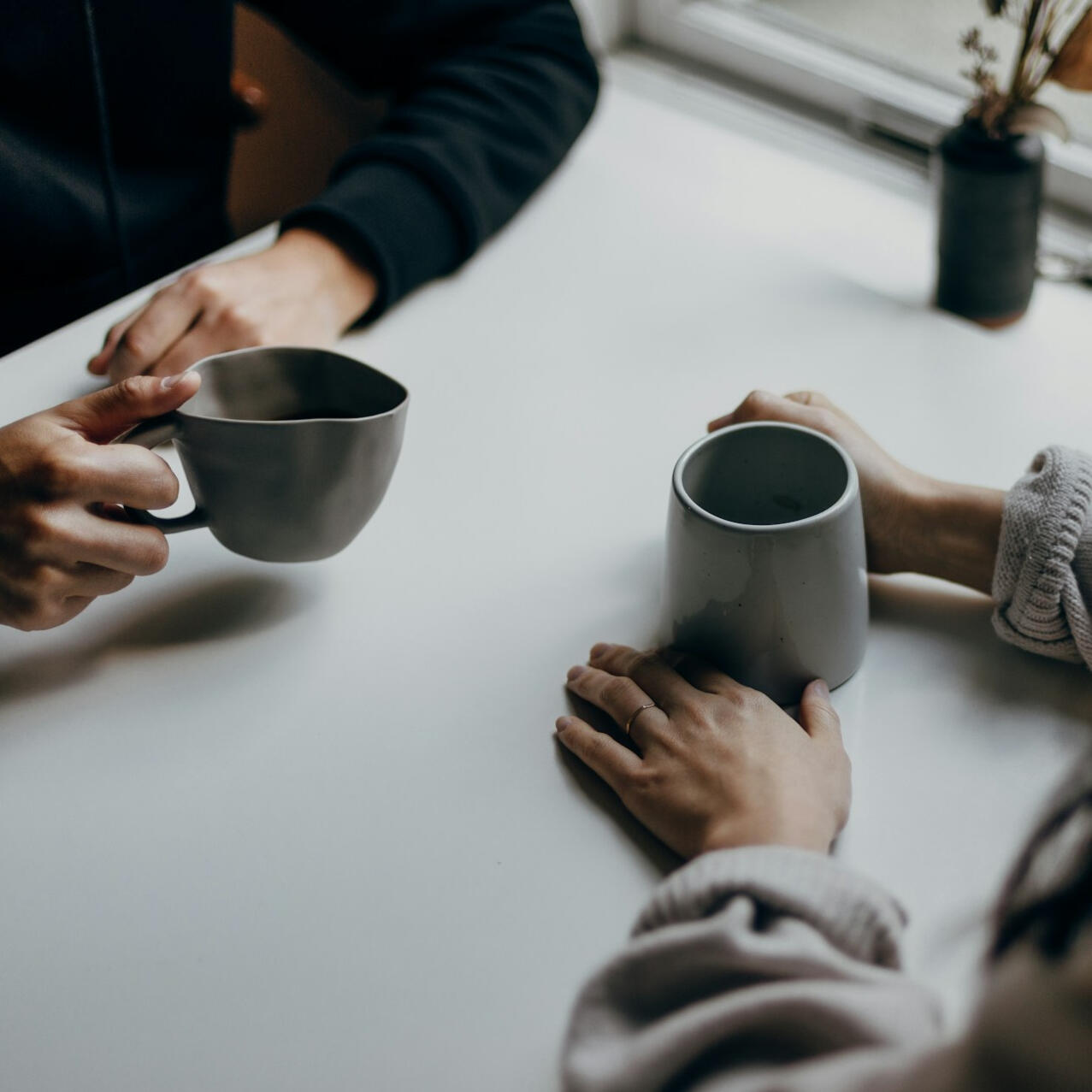 Discovery Meeting Two people sitting at a table holding mugs during a business conversation.