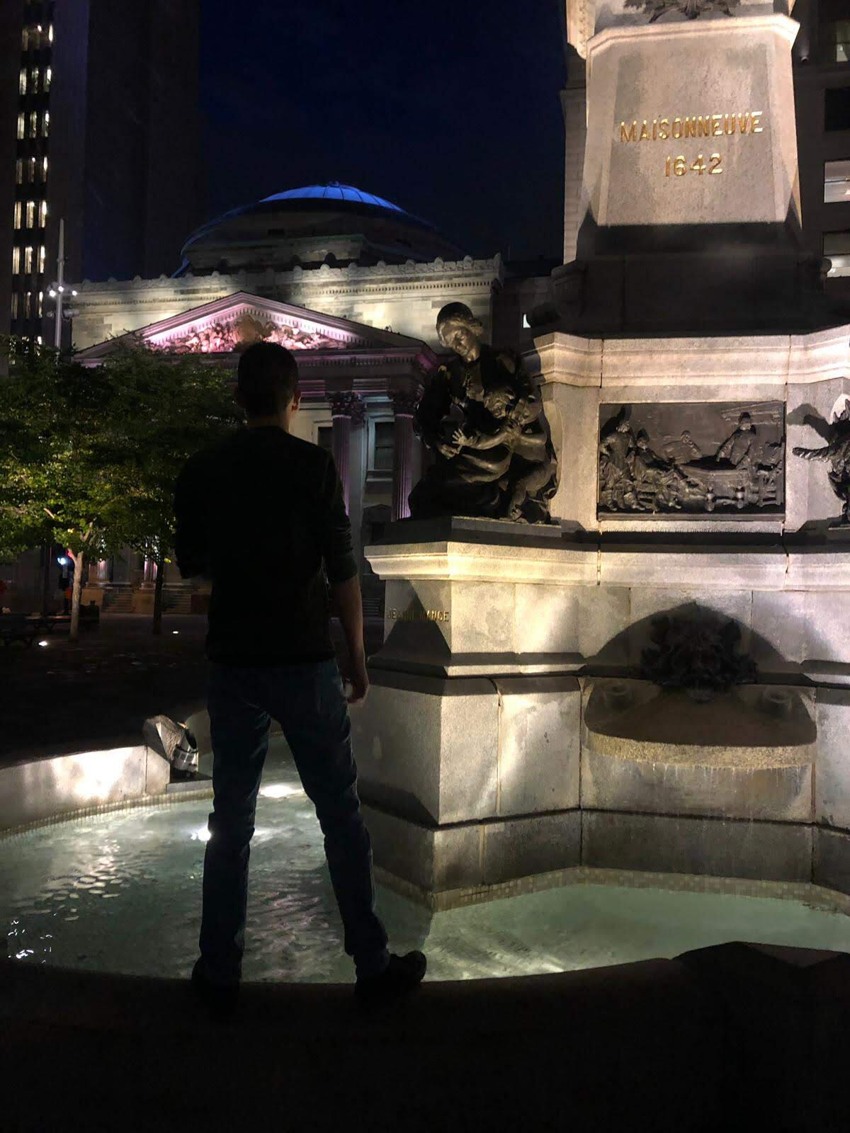 Steve Dinez Steve Dinez standing at the Monument to Paul de Chomedey de Maisonneuve fountain in front of Notre-Dame Basilica in Old Montreal at night.